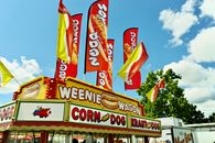 Colorful food truck with flags at a summer carnival serving hot dogs and corn dogs.