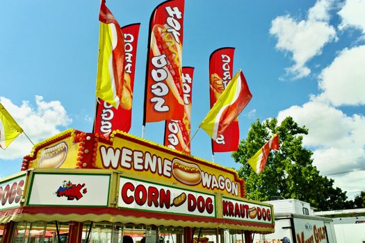 Colorful food truck with flags at a summer carnival serving hot dogs and corn dogs.