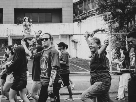 A lively street parade captured in black and white, featuring diverse adults and children enjoying the event.