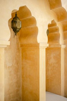 Intricate arches and lanterns showcasing traditional Moroccan design, warm yellow tones.