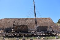 Ancient shipwreck display at archaeological site in Antalya against stone wall.