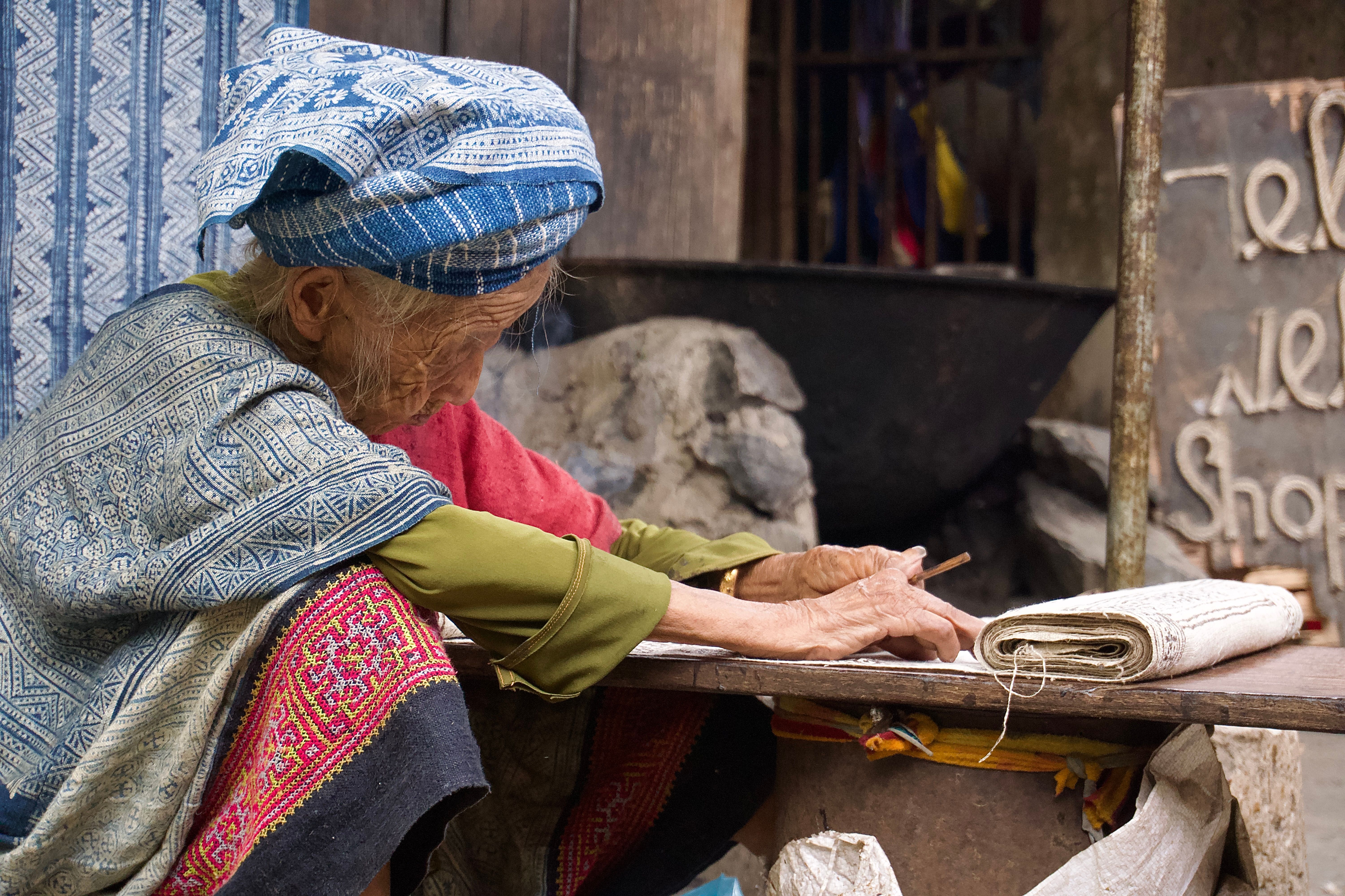 An elderly woman weaving traditional textiles in Lung Tam, Hà Giang, Vietnam, showcasing cultural heritage.
