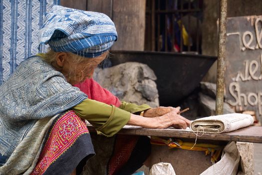 An elderly woman weaving traditional textiles in Lung Tam, Hà Giang, Vietnam, showcasing cultural heritage.