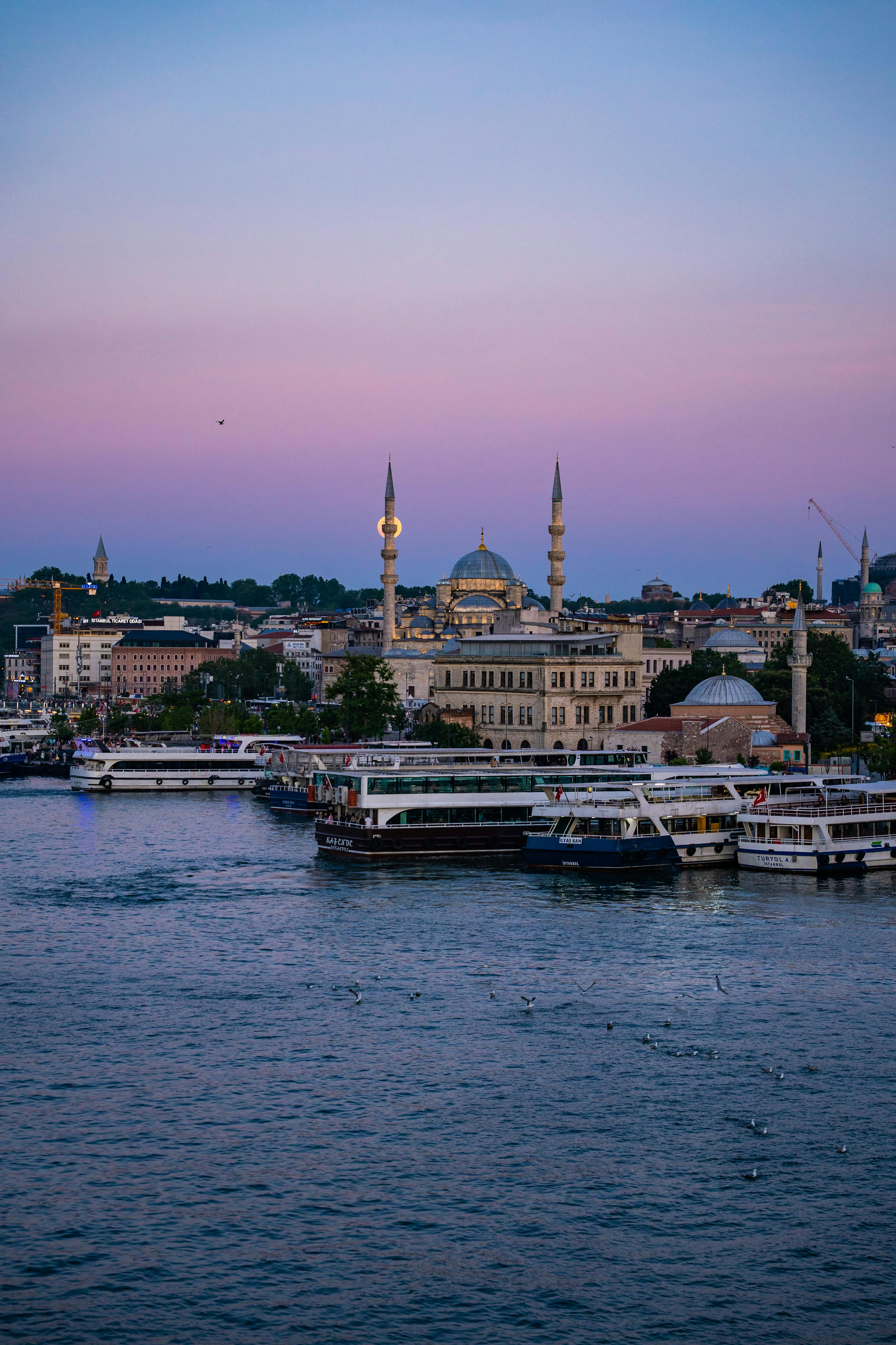 Stunning twilight view of Istanbul's skyline with mosques and boats by the sea.