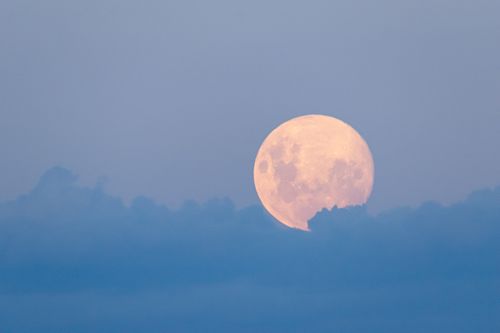 Free A captivating full moon rises above soft clouds during twilight, creating a serene and dreamy atmosphere. Stock Photo