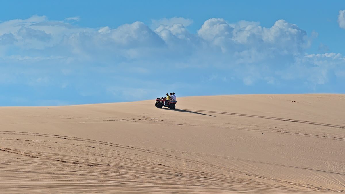 ATV quad cresting open sand dunes in the desert
