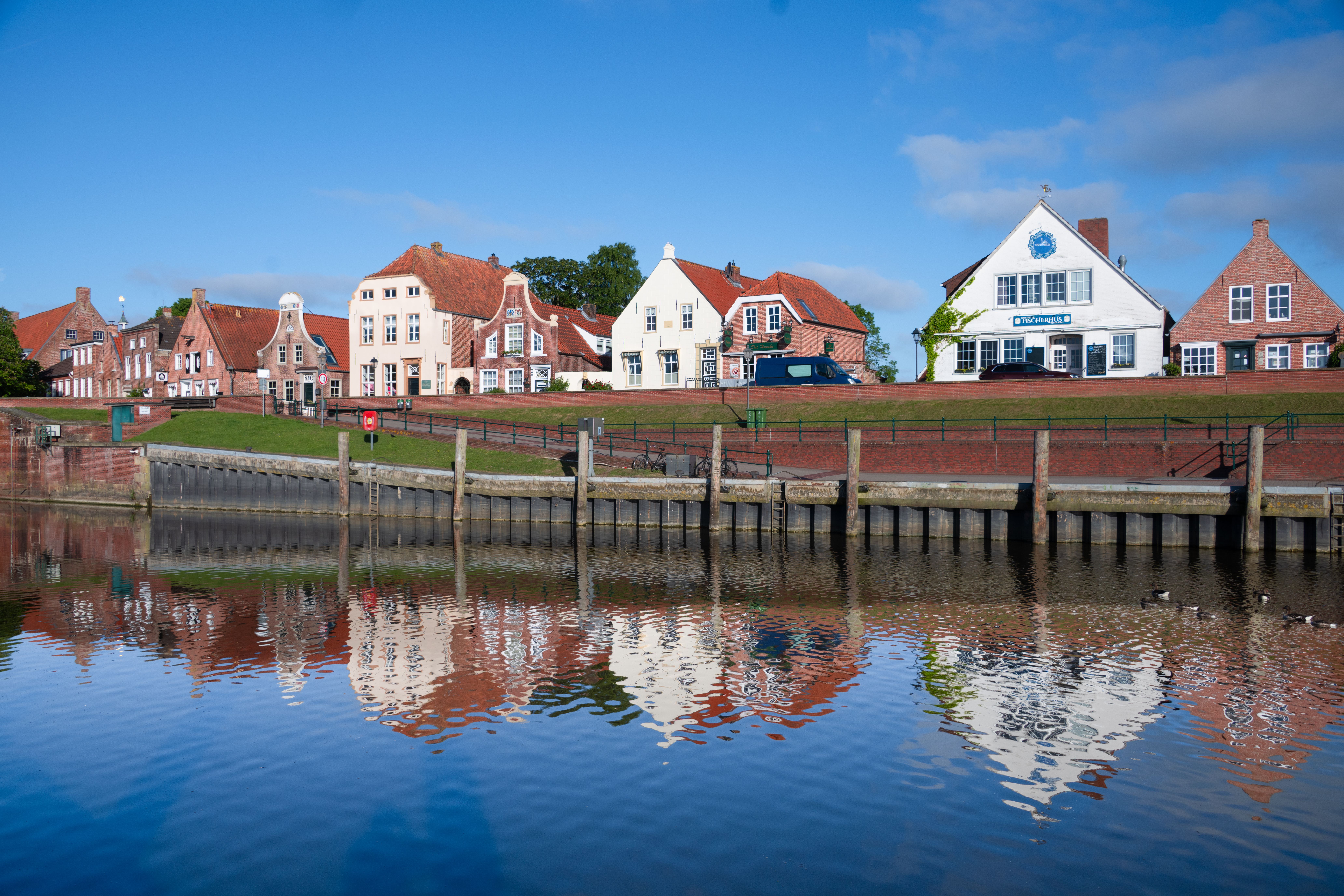 Charming waterfront view of traditional houses reflecting in calm waters, embodying idyllic German coastal architecture.