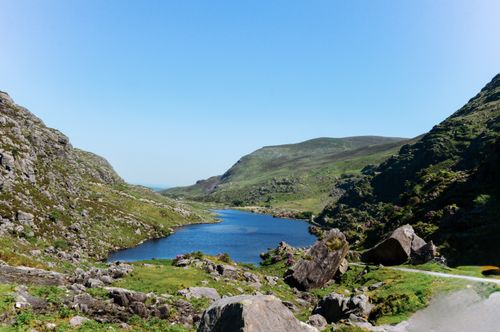 Free Breathtaking landscape of the Gap of Dunloe in Ireland, featuring a serene lake surrounded by rocky mountains under a clear blue sky. Stock Photo