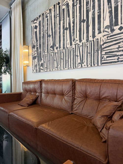 Free Luxurious brown leather couch in a stylish modern living room with artistic wall decor. Stock Photo