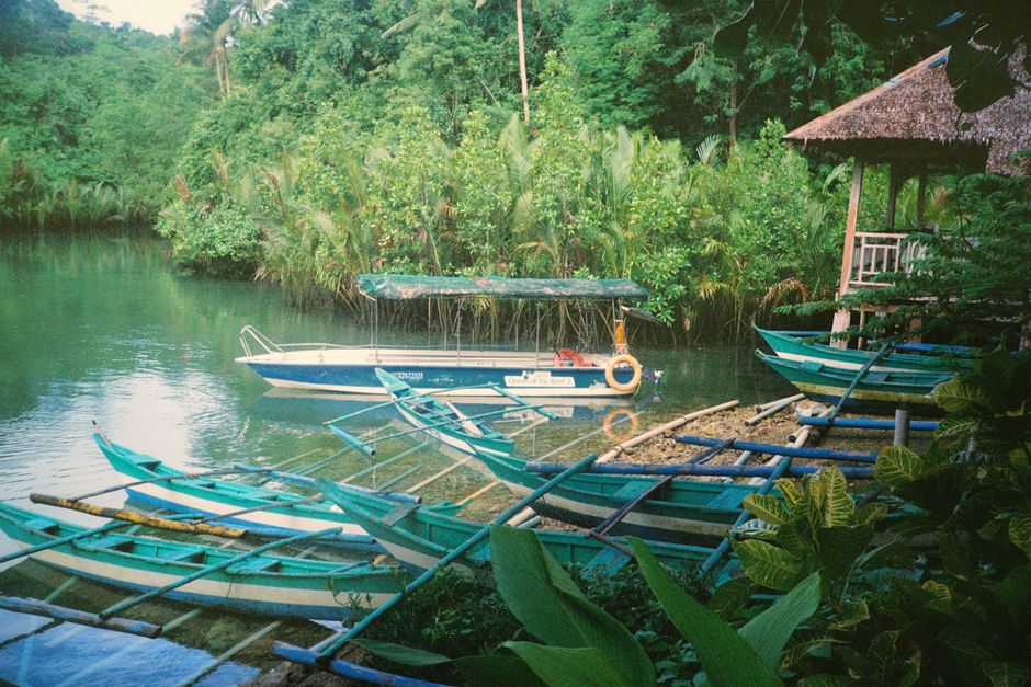 Serene river with traditional Filipino boats and lush greenery in the Philippines.