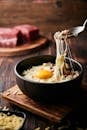 木板上放着一碗美味的融化奶酪和鸡蛋，背景是牛肉