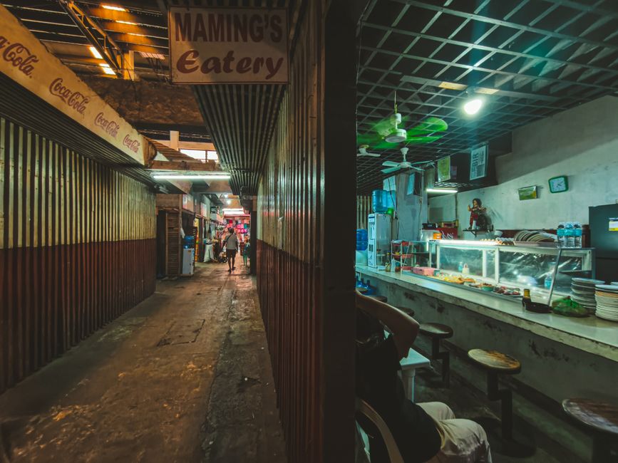 A bustling Filipino carinderia, a local eatery in the Philippines, with various dishes on display