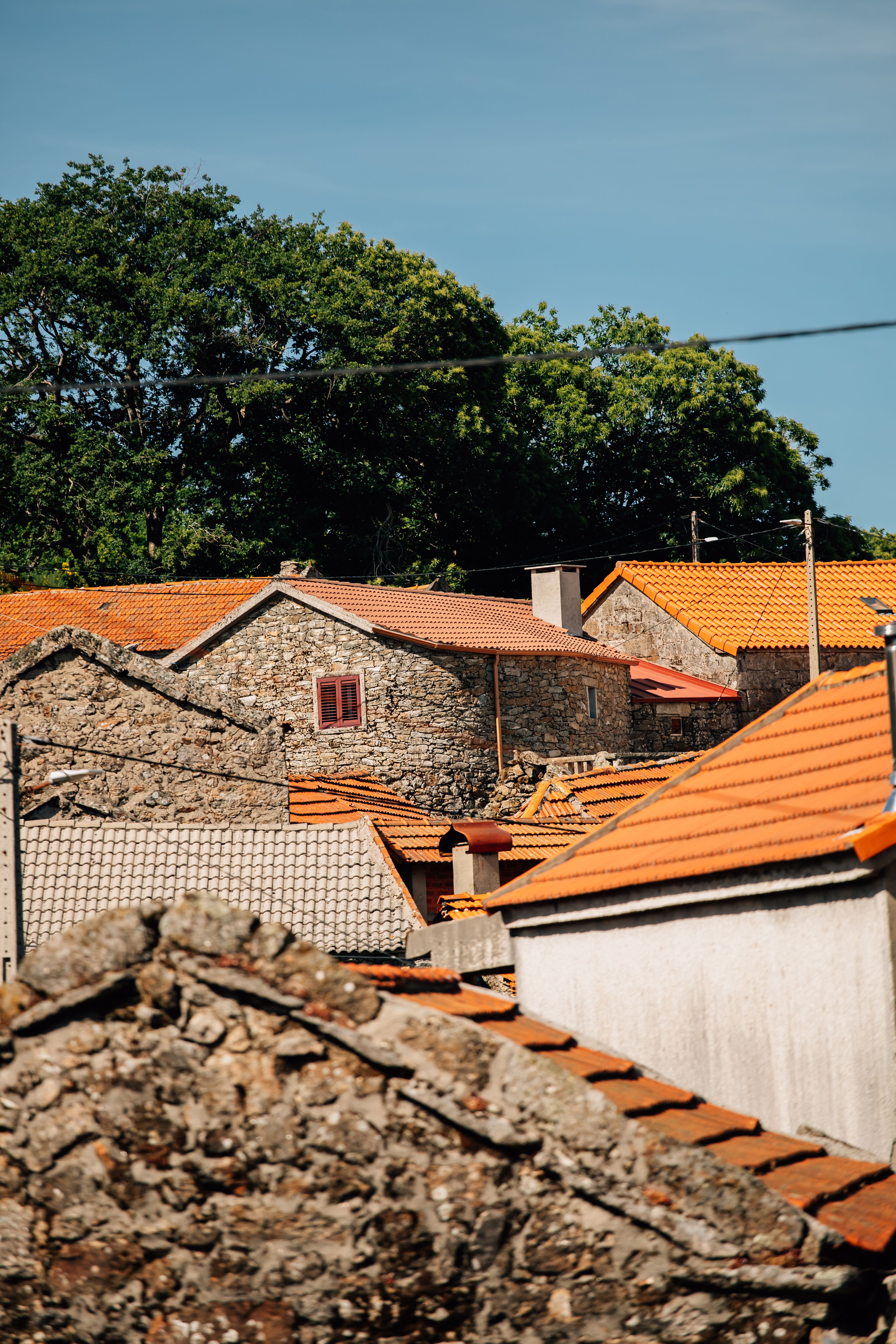 Rustic stone buildings with red roofs in Montalegre, Portugal, under a clear sky.