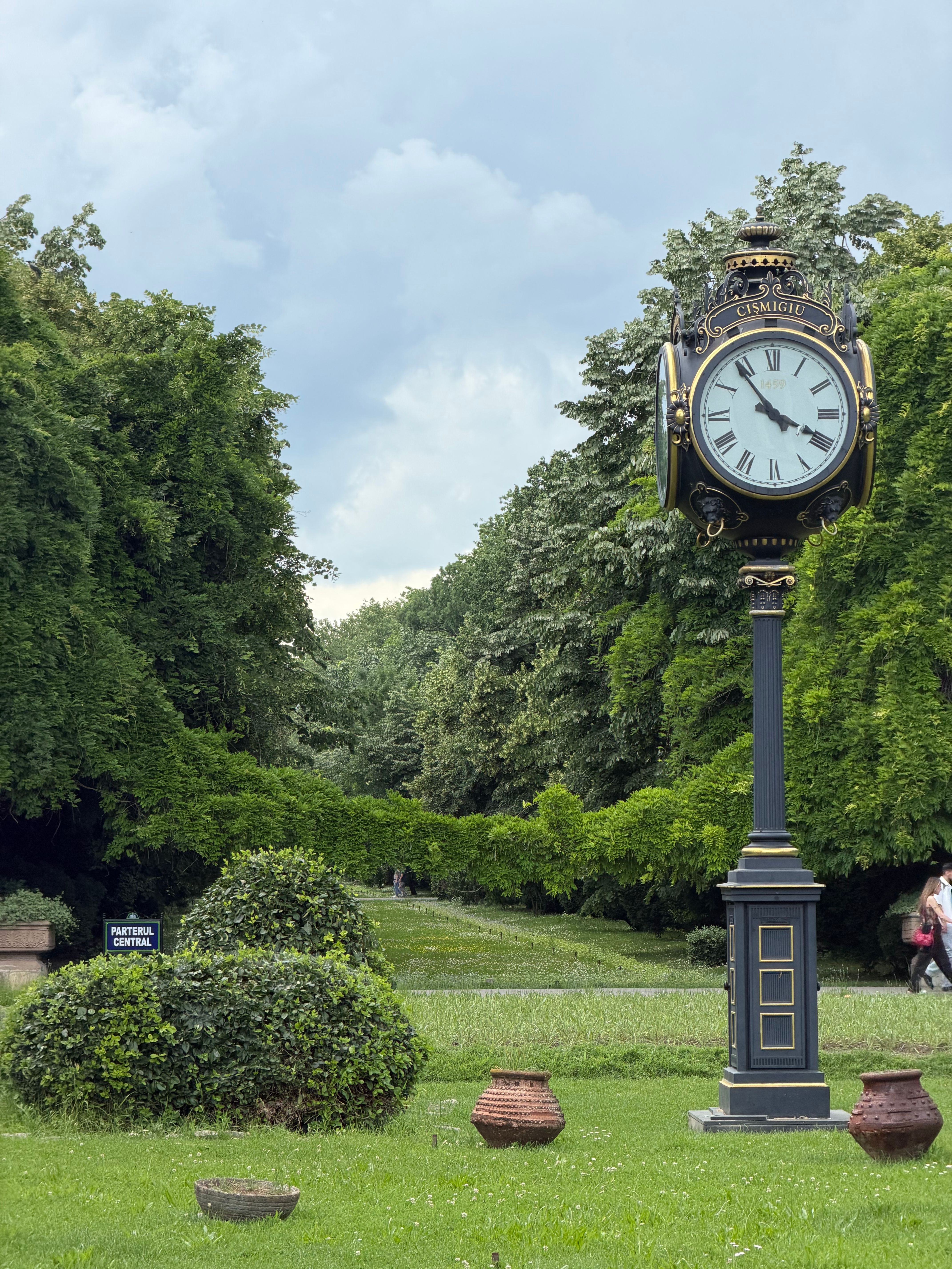 An ornate clock stands in lush Parcul Regele Mihai I, Bucharest, capturing timeless elegance.