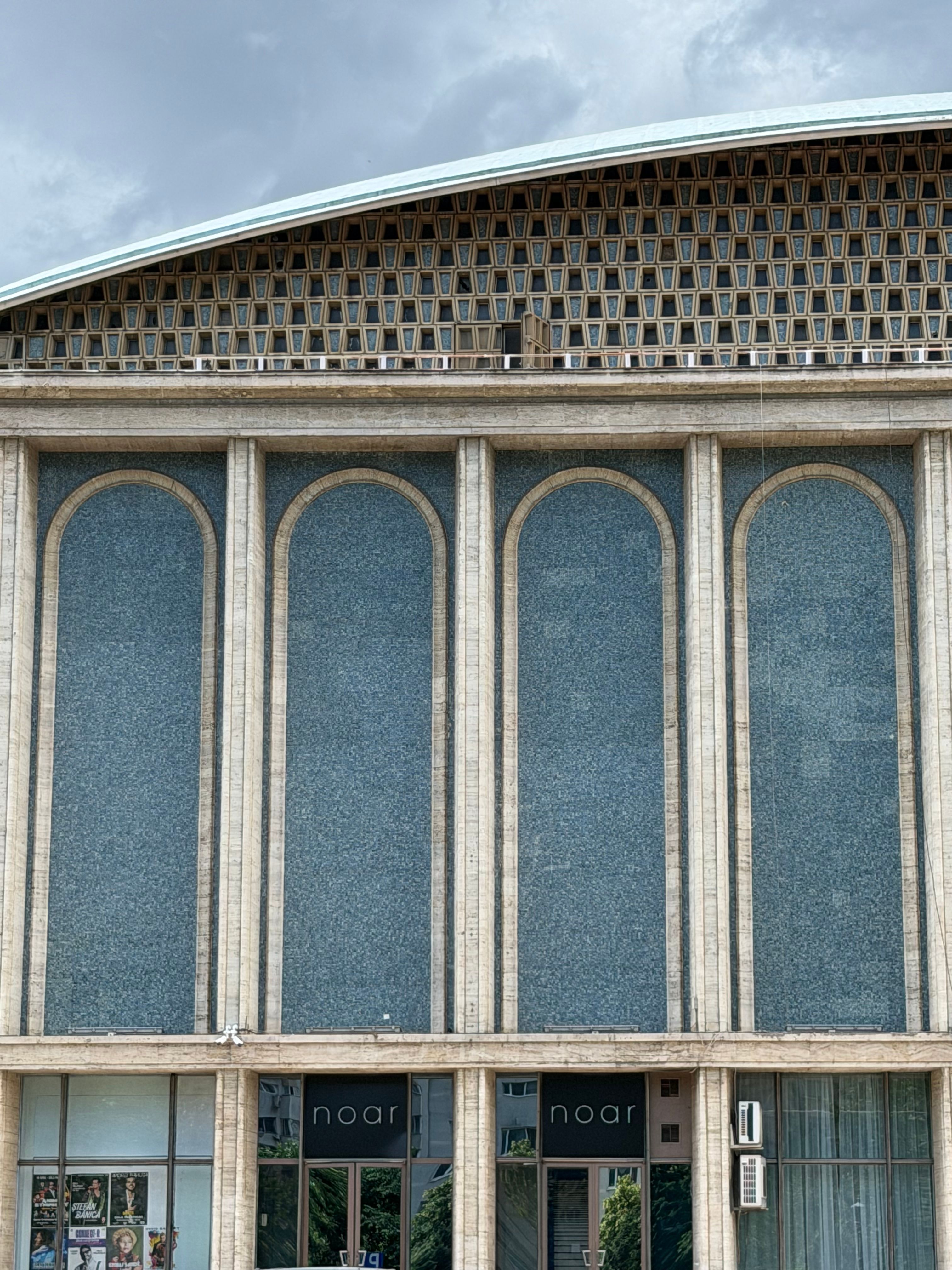 Modernist facade of Noar building with tall blue-tinted windows in urban setting.