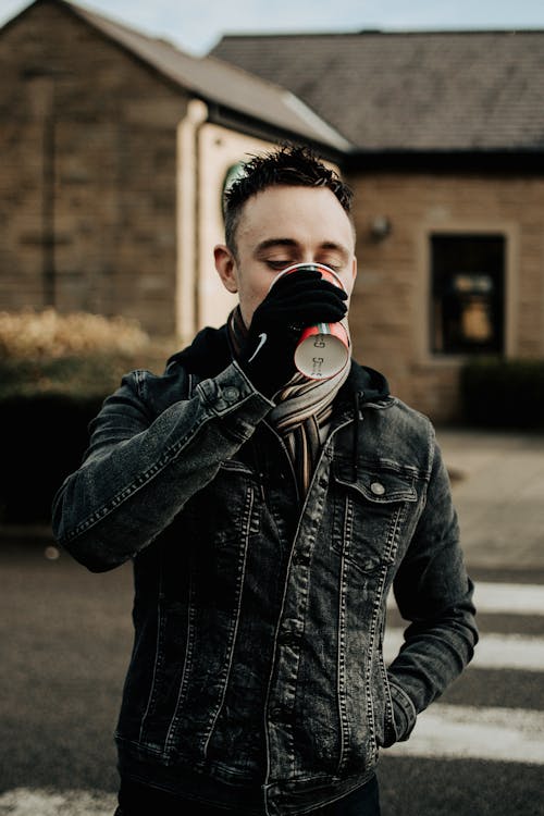 Homme En Veste En Cuir Noir De Boire Dans Une Tasse Jetable Blanche Et Rouge