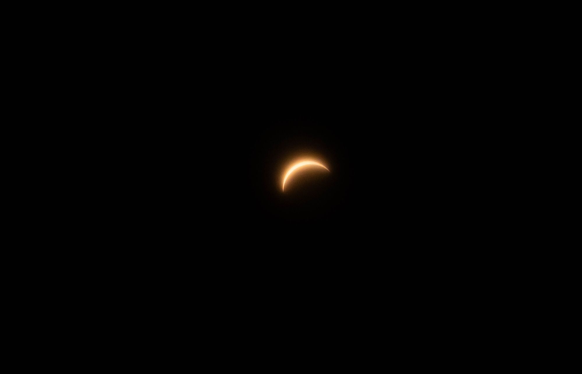 Grupo de personas mirando al cielo con gafas de eclipse mientras el Sol baja hacia el horizonte