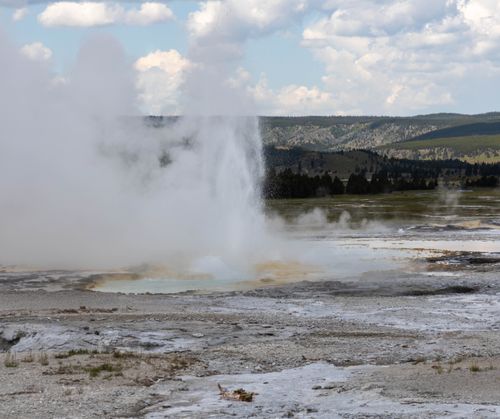 Free A geyser erupts in Yellowstone National Park, showcasing nature's raw power amid scenic landscapes. Stock Photo