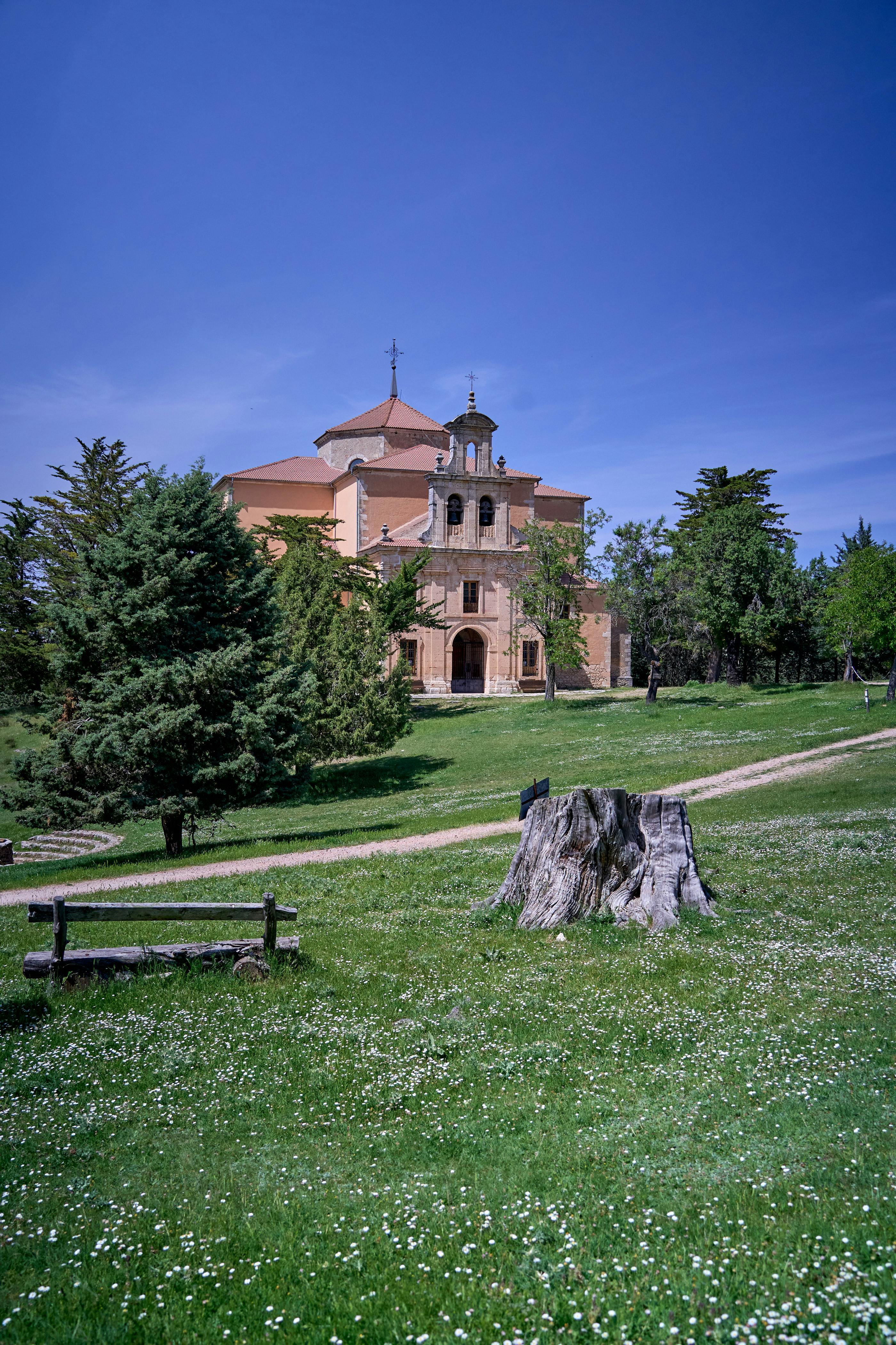Scenic view of Maderuelo's historic church amidst lush greenery and bright blue skies.