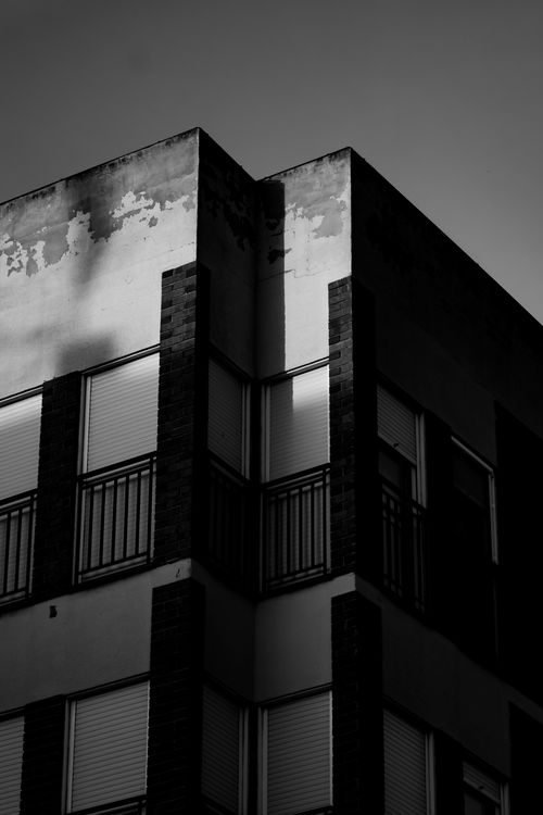 Free Black and white photo capturing a corner of a modern urban building against a dark sky. Stock Photo