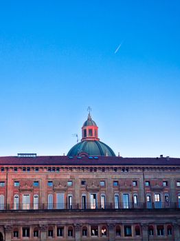 Beautiful view of a historic dome in Bologna, Italy, with a clear blue sky and contrail at sunrise.
