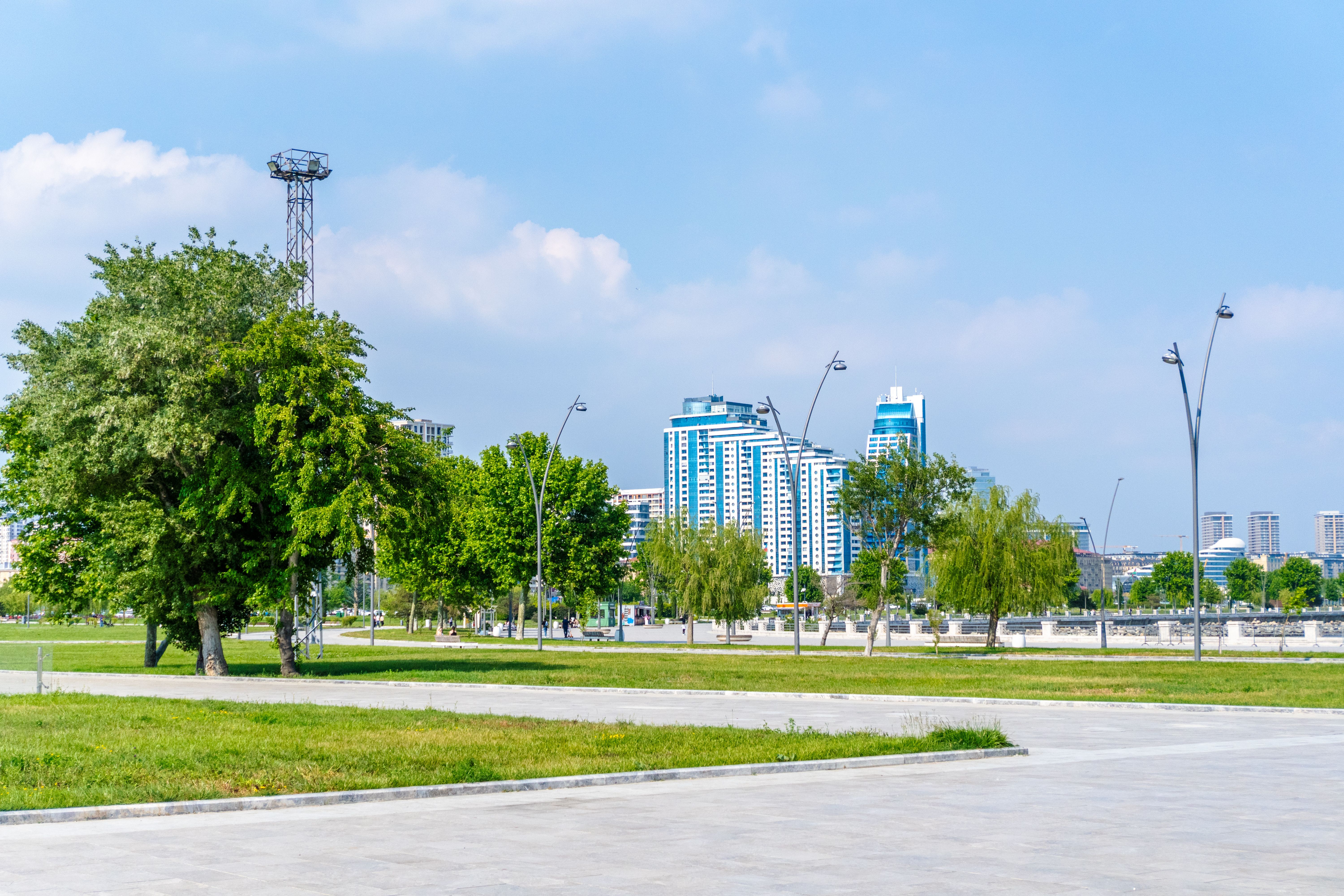 Skyline view of Baku with lush park greenery, showcasing modern architecture against a clear blue sky.