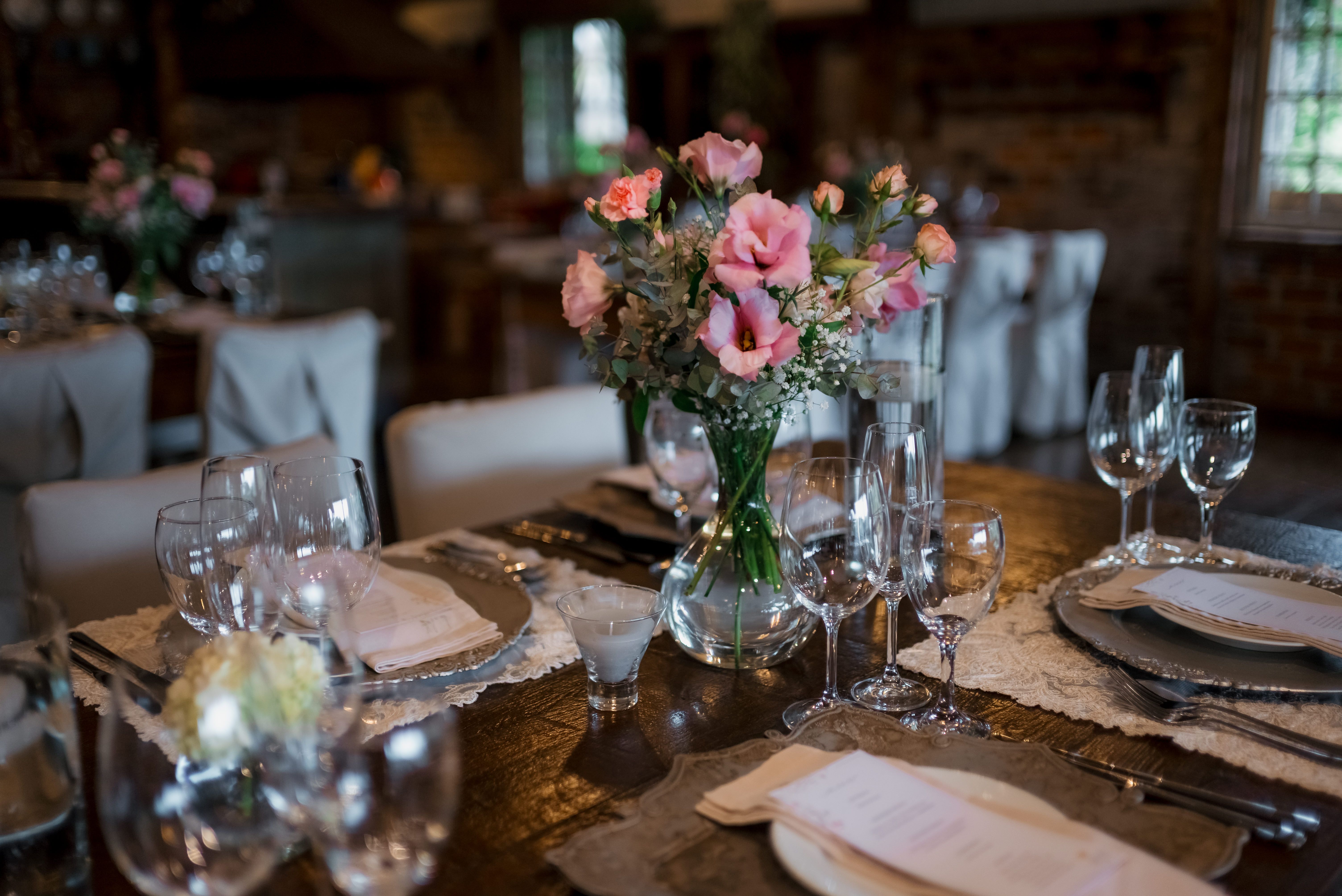 Charming wedding reception table with pink floral centerpiece and elegant glassware.