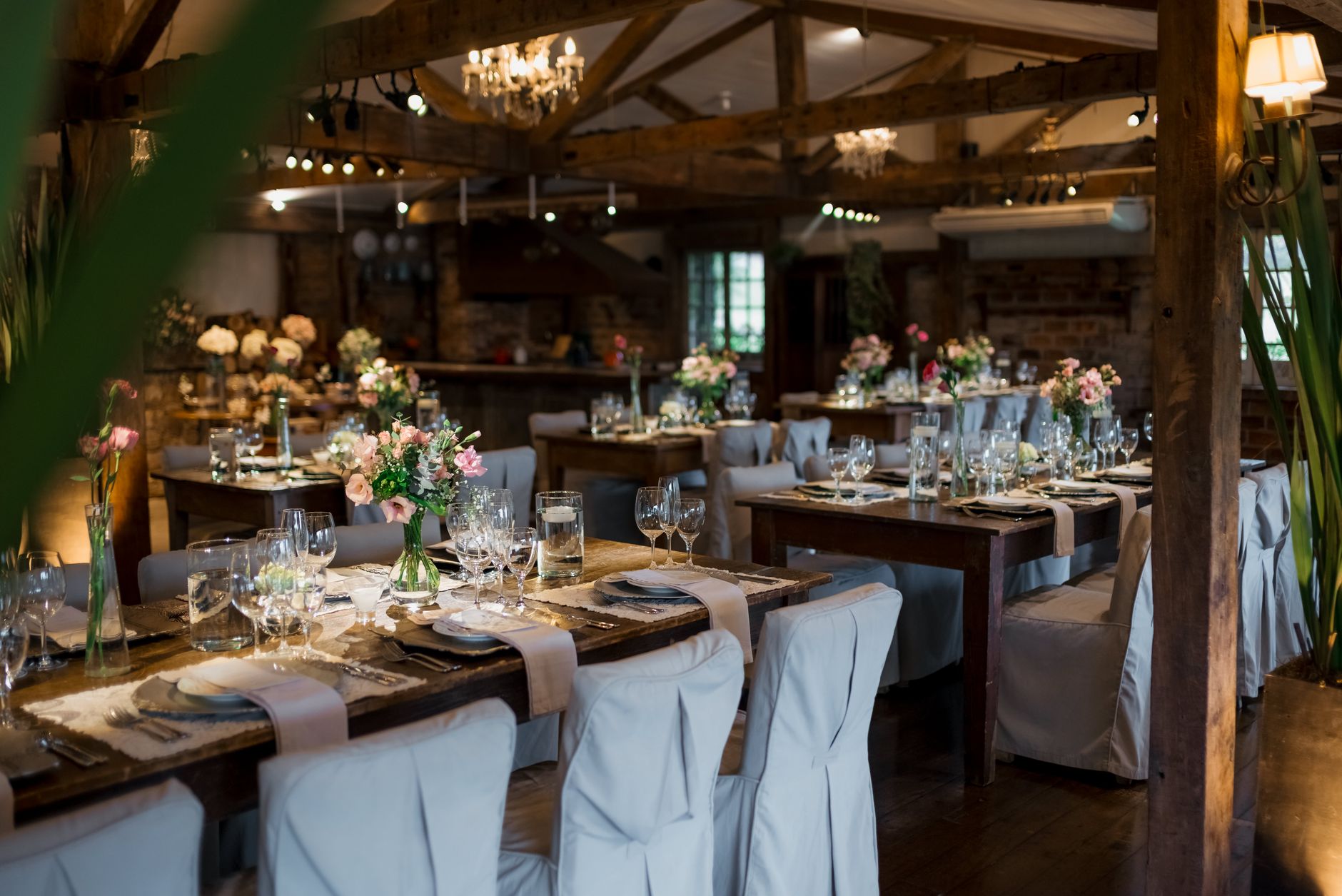 Beautifully decorated rustic wedding reception with floral centerpieces and covered chairs.