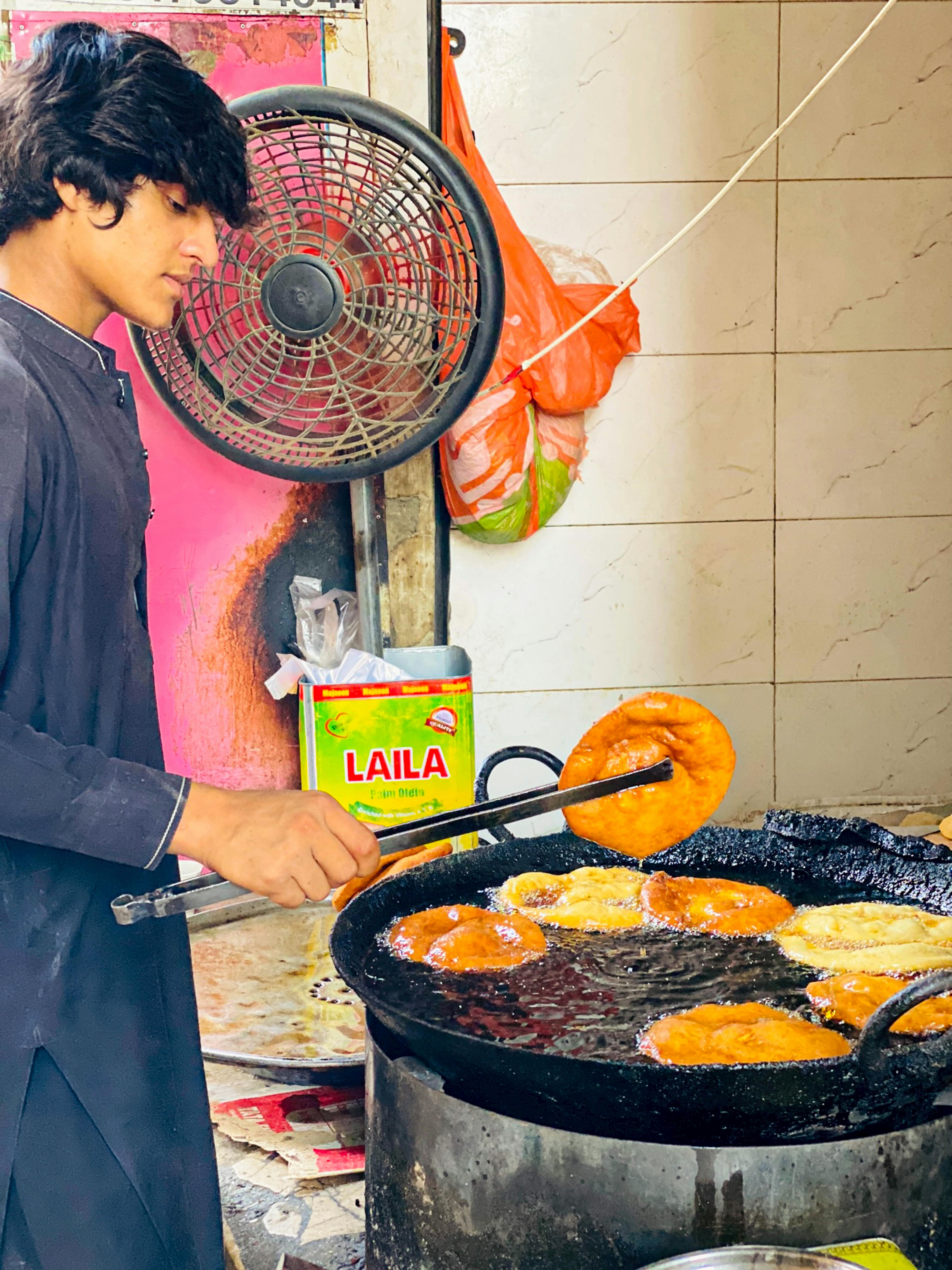 A young chef frying traditional Swat sweet bread on a street in Mingora, Pakistan.