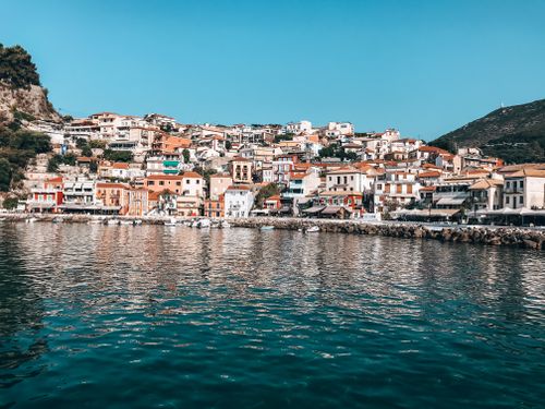 Free Picturesque view of a colorful Greek coastal town with vibrant houses and serene waters, under a clear blue sky. Stock Photo