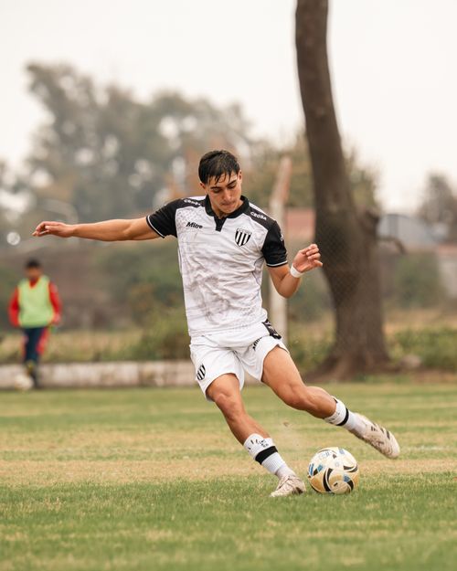 Free A young soccer player skillfully kicking the ball on a grassy field during a match. Stock Photo