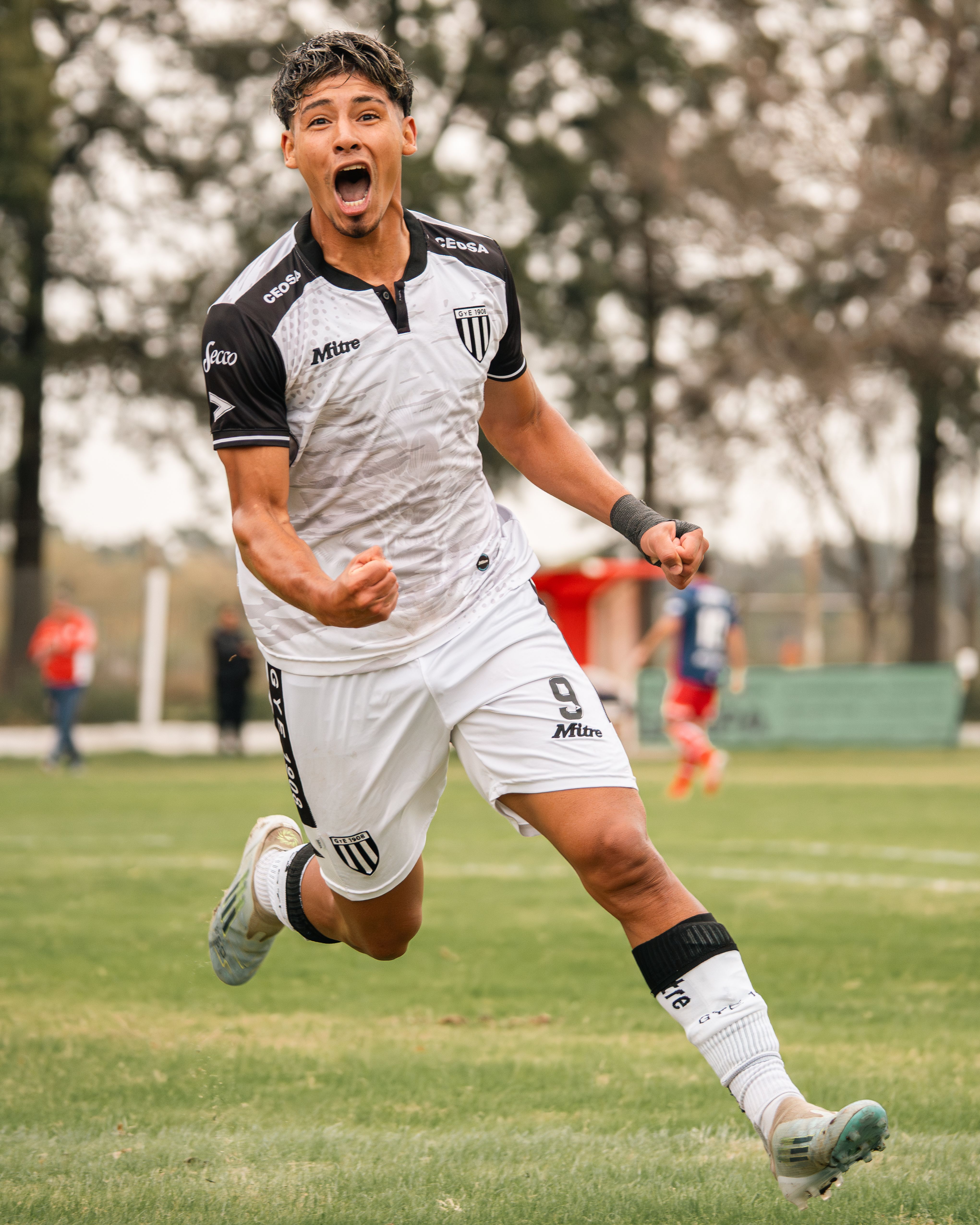 Excited soccer player in action celebrating a goal on the field.