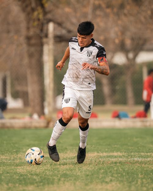 Free A young male soccer player focuses intensely as he dribbles a ball on a grassy outdoor soccer field. Stock Photo