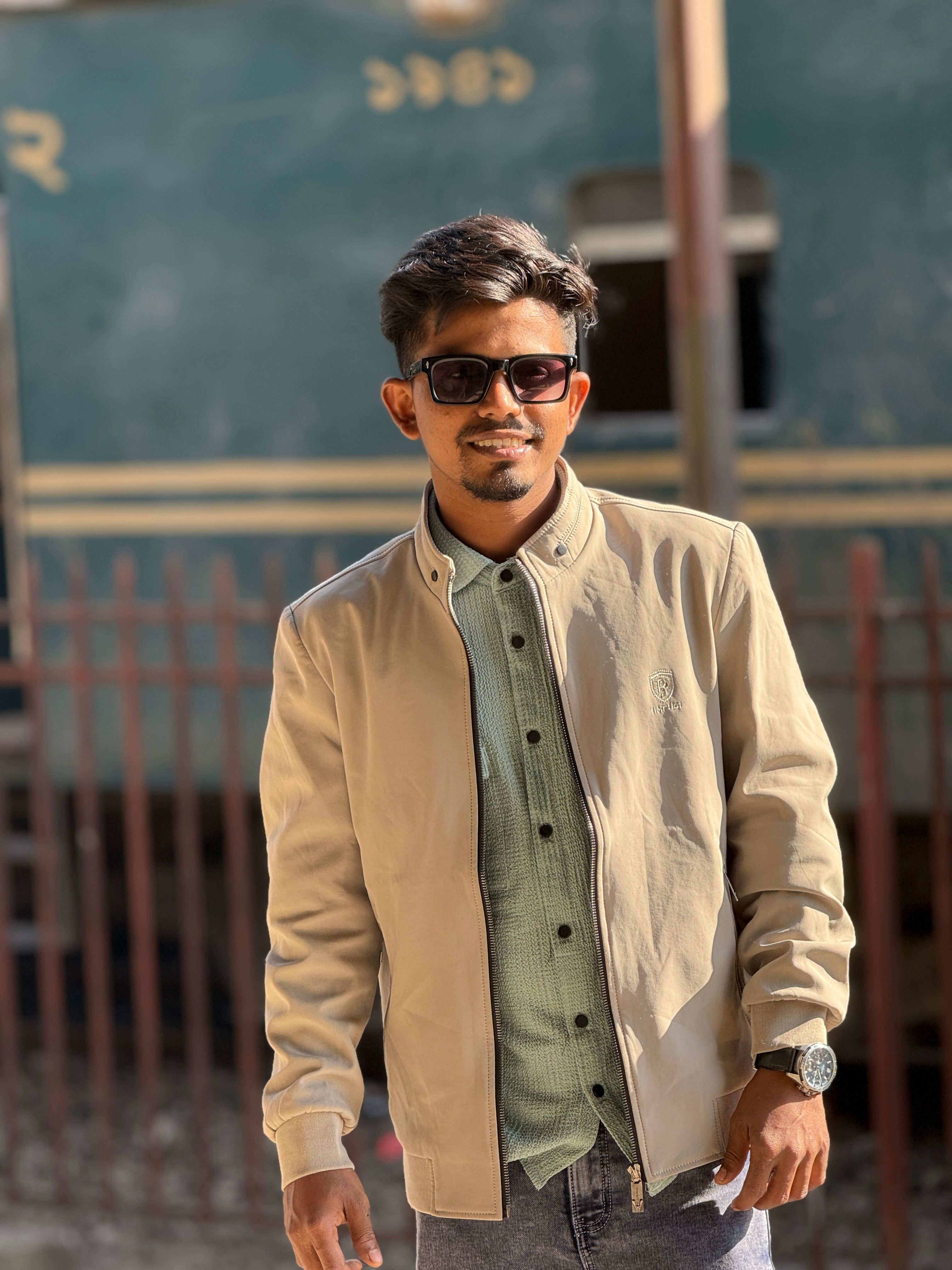 Casual young man in sunglasses posing by a vintage train.