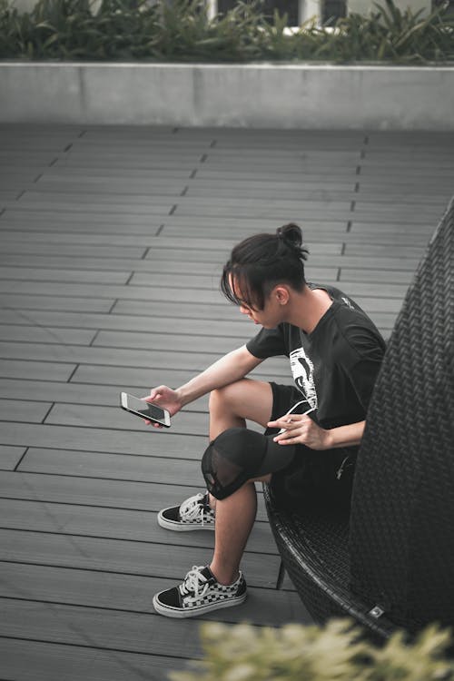 Unrecognizable ethnic man surfing internet on smartphone while smoking cigarette