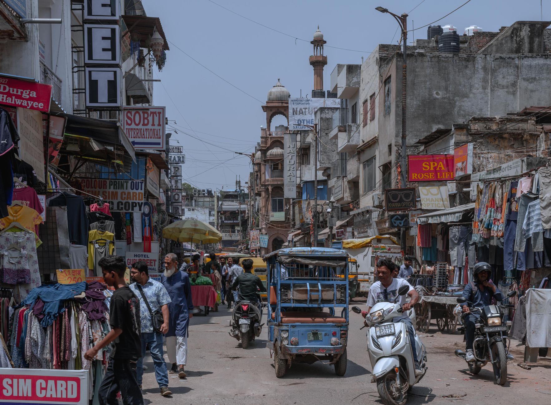 Pedestrianised Ajmal Khan Road in Karol Bagh lined with clothing shops and street food carts at dusk