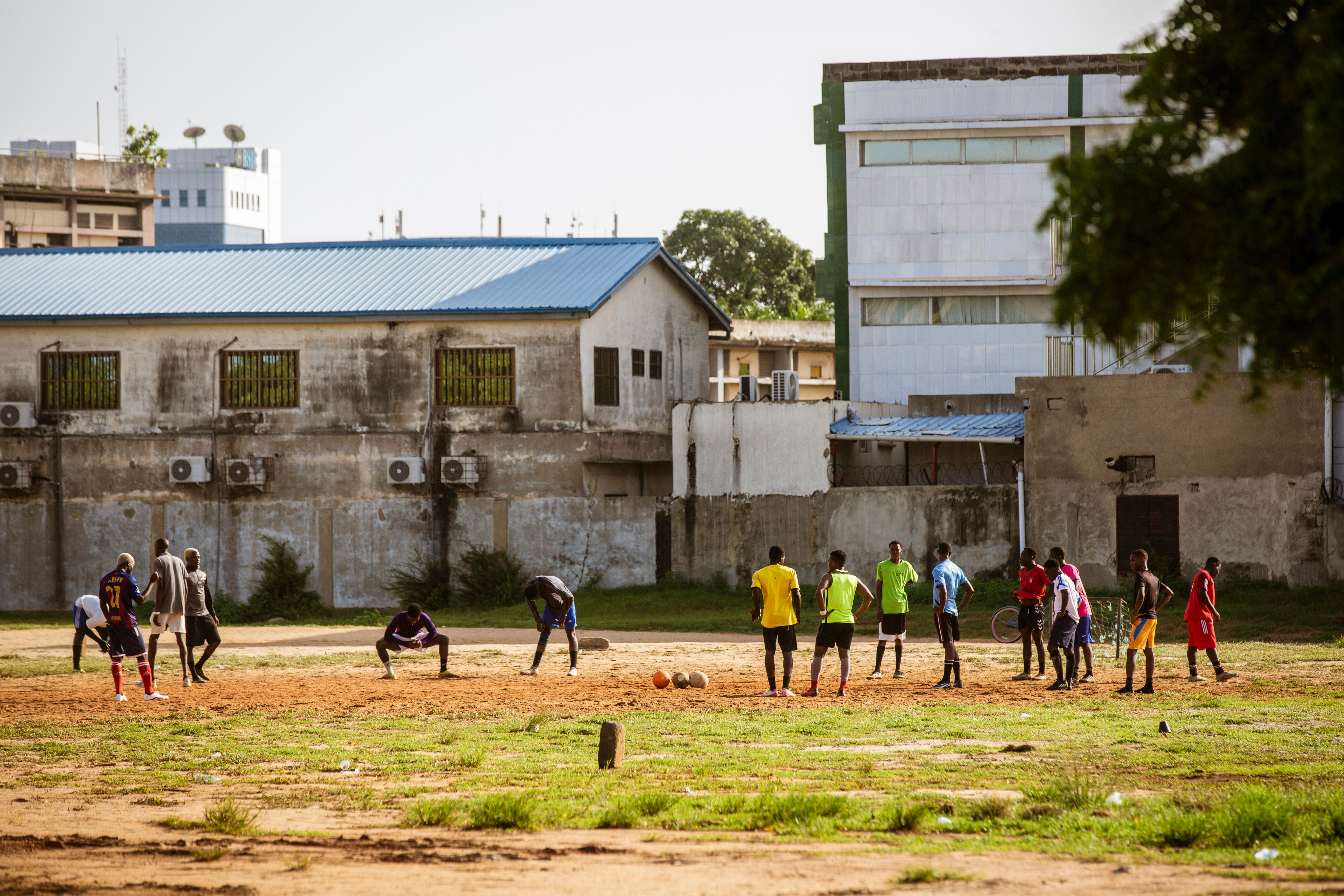 A lively street soccer game with young adults in Lomé, Togo on a sunny day.