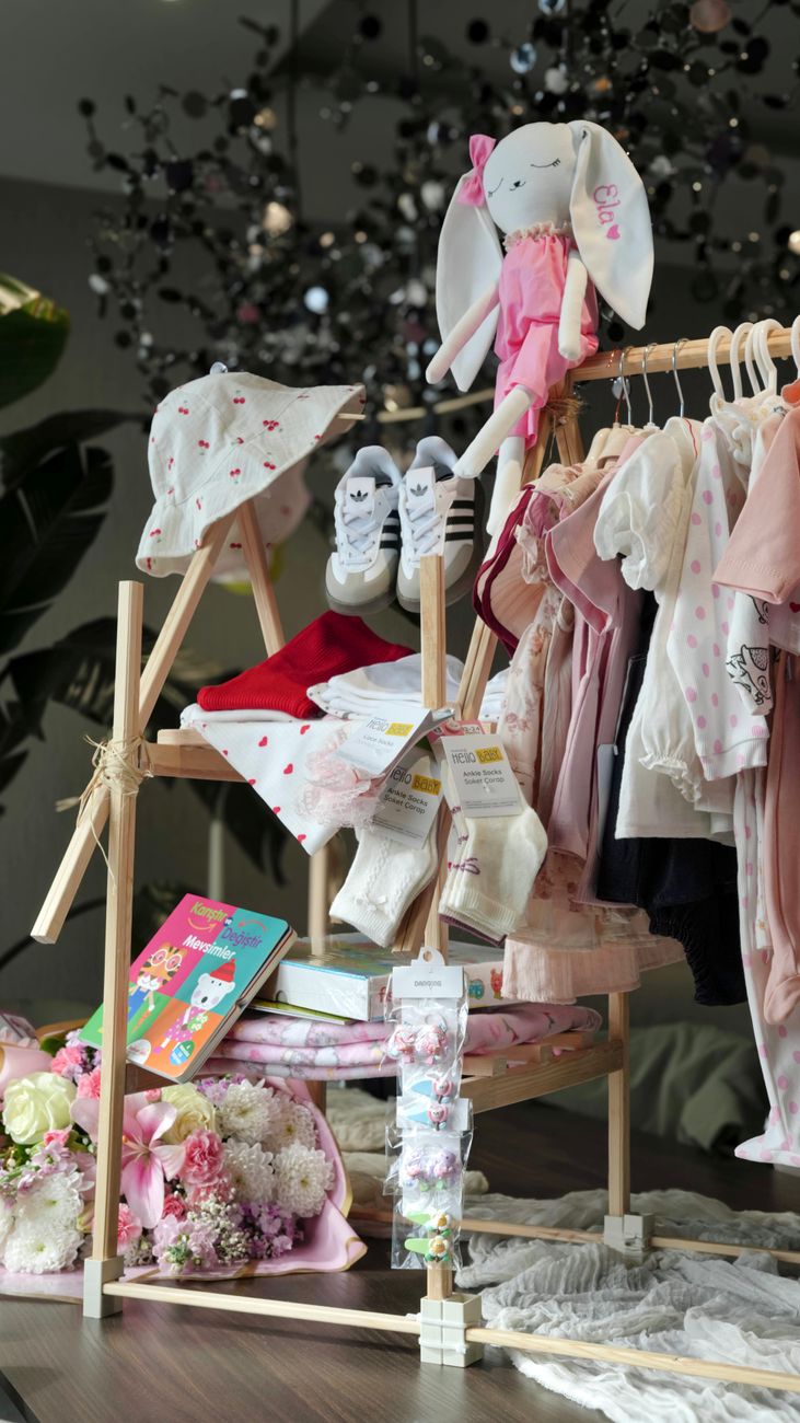 Conjunto de roupinhas de bebê dobradas ao lado de bichinhos de pelúcia, organizados como presente de chá de bebê