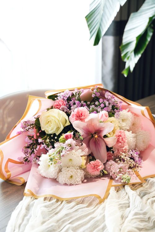 Free A beautiful floral arrangement featuring roses, lilies, and chrysanthemums on a table. Stock Photo