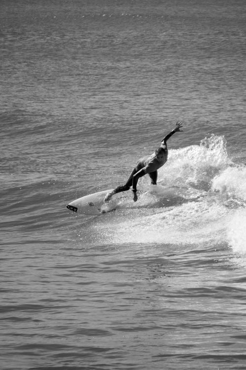Free A surfer skillfully rides a wave in a dramatic black and white scene. Stock Photo