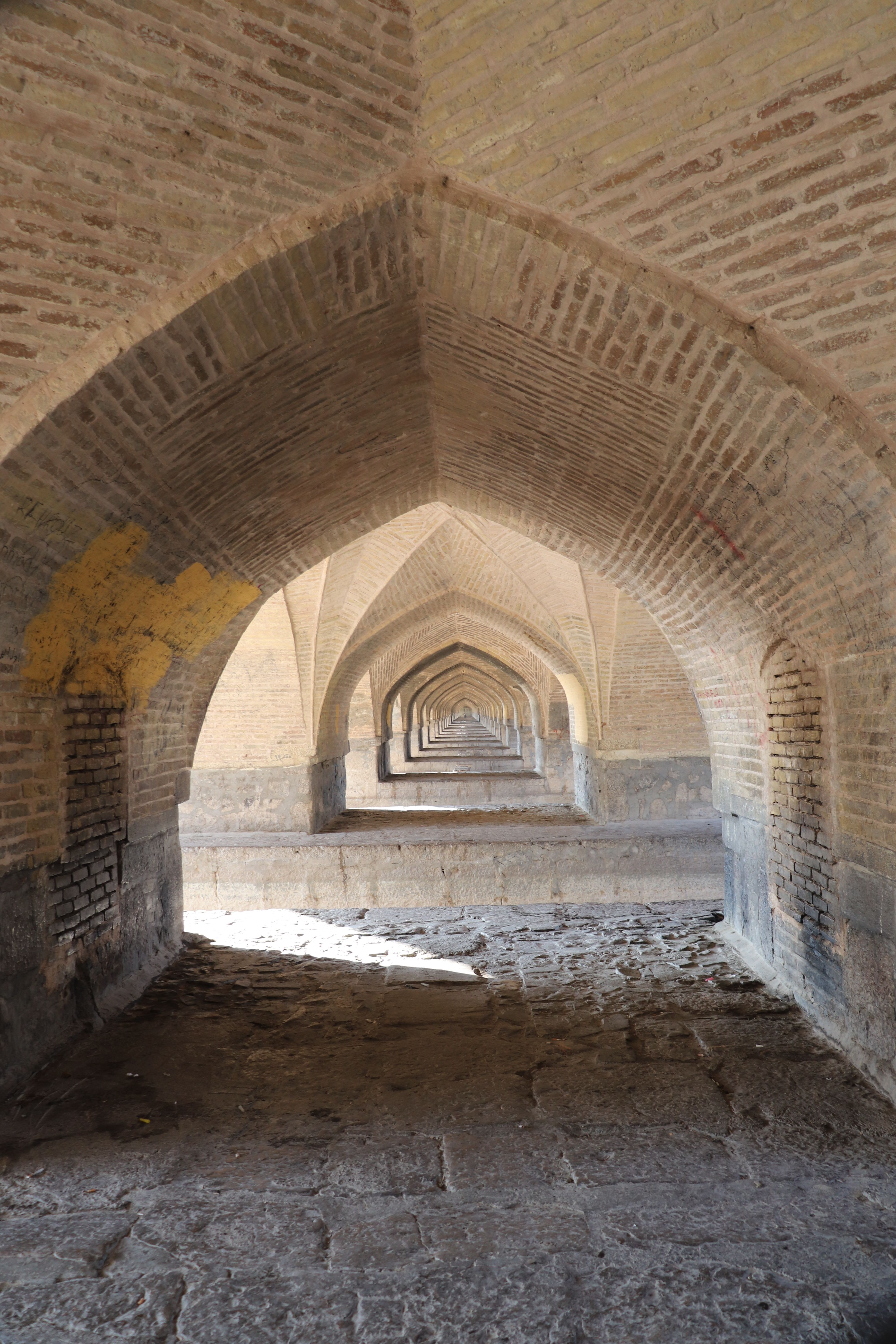 View of a historic arched corridor made of stone and brick, showcasing architectural symmetry.