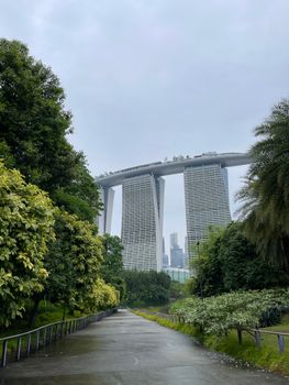 View of Marina Bay Sands from Gardens by the Bay with lush greenery on a cloudy day.