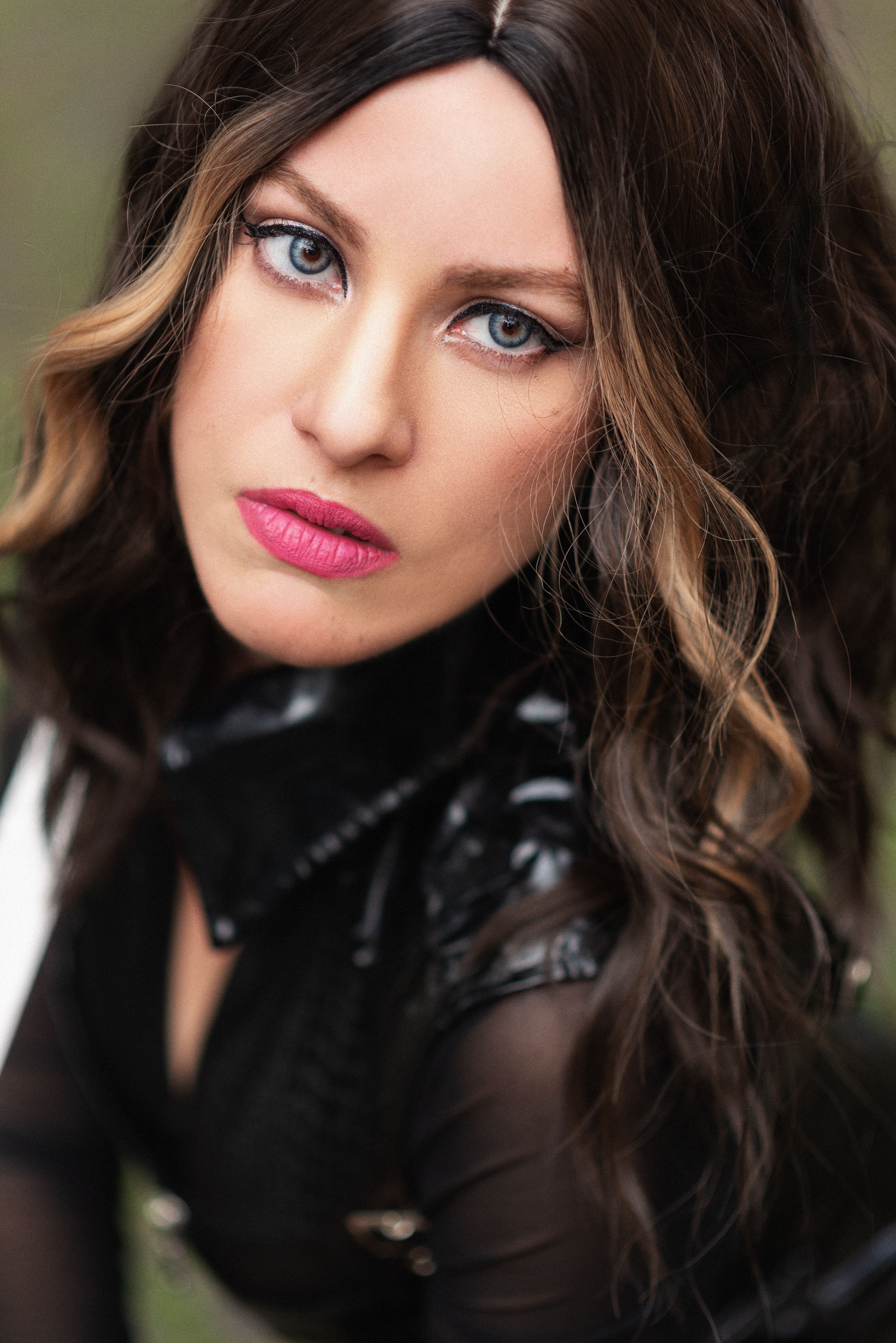 Close-up portrait of a woman with striking blue eyes in a leather jacket.