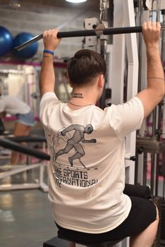 Man using a weight machine at the gym, focusing on back muscles, a healthy lifestyle and fitness routine.
