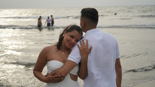 Free A loving couple embracing on a sandy beach at sunset, capturing a romantic moment by the sea. Stock Photo