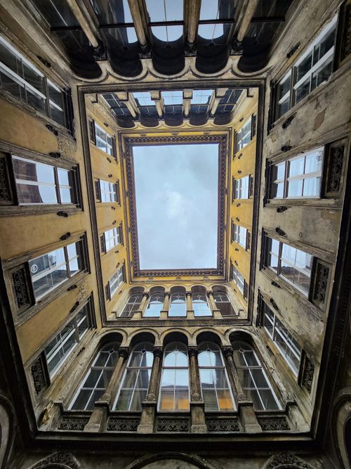 Free Impressive view from the bottom of a historic courtyard with ornate architecture and open sky. Stock Photo