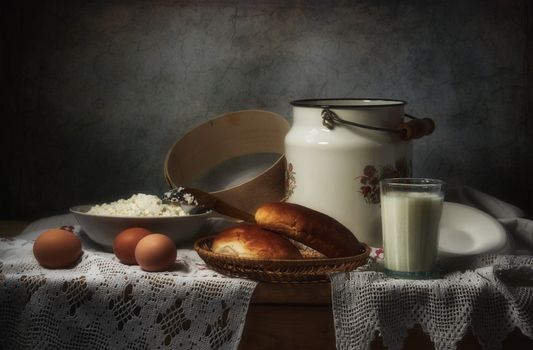Artistic still life of cottage cheese, eggs, bread, and milk on a lace cloth.