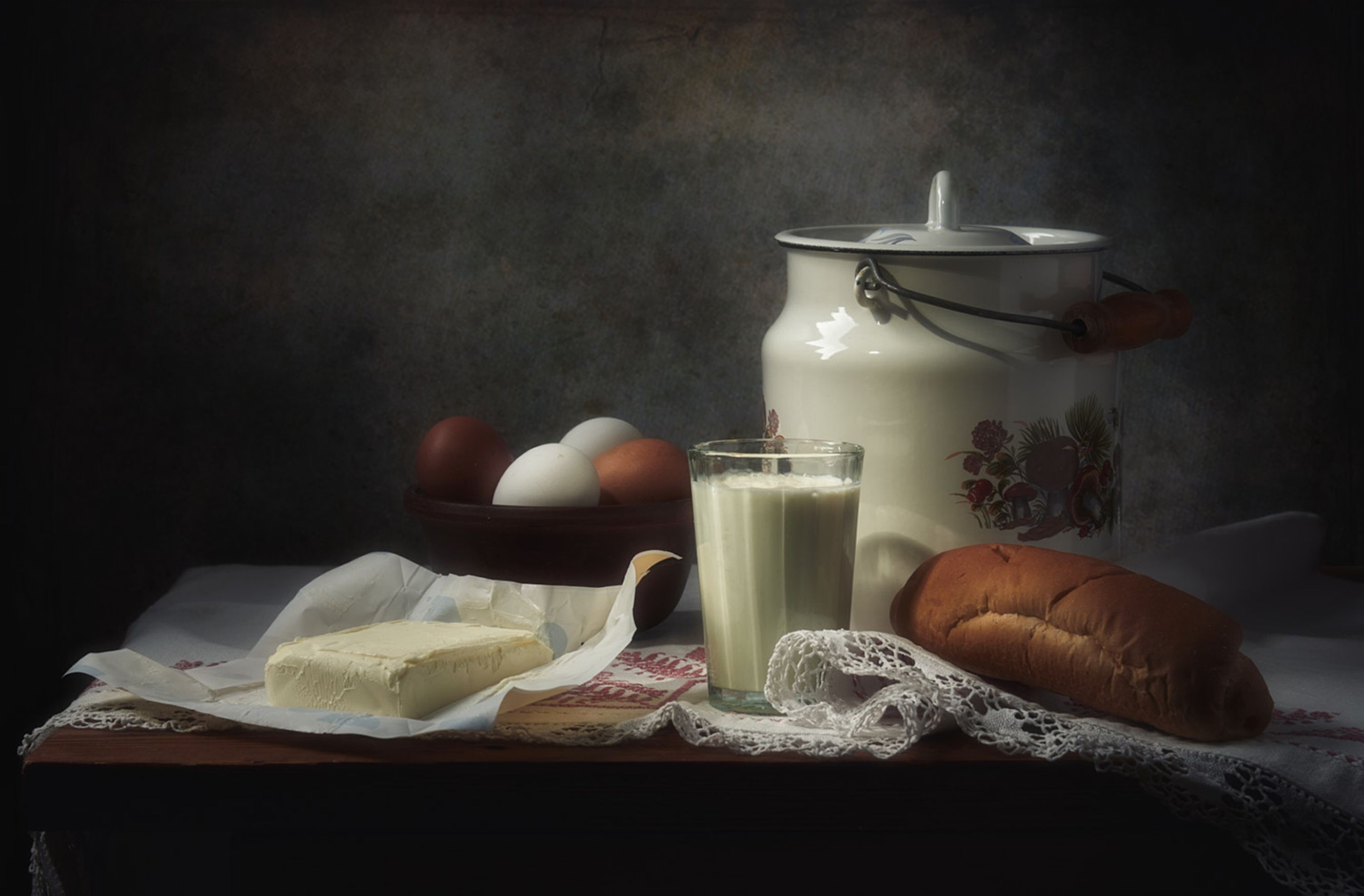 A classic still life of farmhouse breakfast items on a wooden table.
