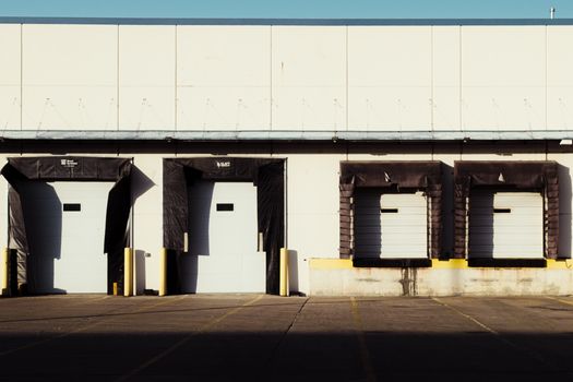 An industrial loading dock with closed bay doors, captured in bright daylight.