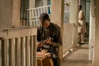 A young man skillfully crafting wooden items in a corridor setting in Nigeria.